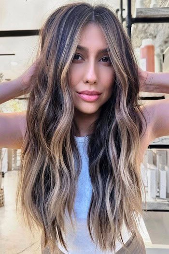 Brunette With Face-Framing Blonde Highlights hair color on a woman with long brown hair.