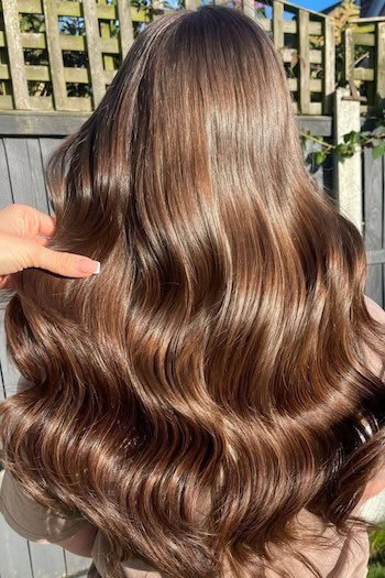 Chestnut Brown Hair With Glossy Waves hair color on a woman with long shiny brown hair, back view.