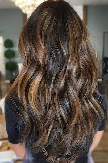 Golden Caramel Highlights On Espresso Brown Hair on a woman with long wavy hair, back view.