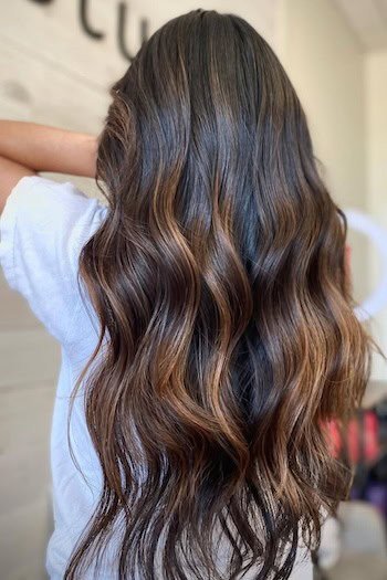 Subtle Copper Balayage Flowing Through Deep Mocha Brown Hair on a woman with brown hair, back view.
