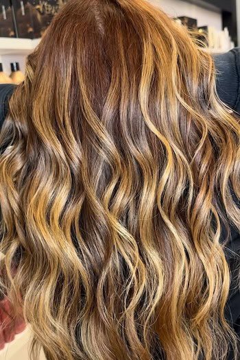 Golden Brown With Blonde Streaks hair color on a woman with brown hair, back view.